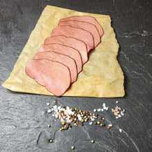 Pastrami in Scheiben aufgeschnitten mit bunten Pfefferkörnern auf Schieferhintergrund