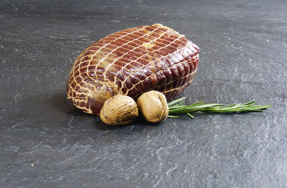 Nussschinken angerichtet mit zwei Walnüssen und Rosmarin auf Schieferhintergrund