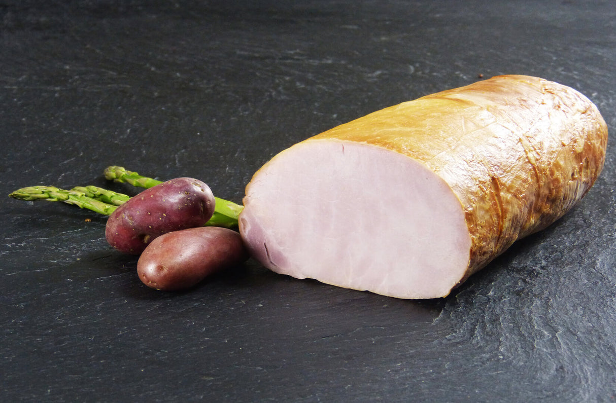 Kasseler ohne Knochen gekocht angerichtet mit grünem Spargel und zwei Süßkartoffeln auf Schieferhintergrund