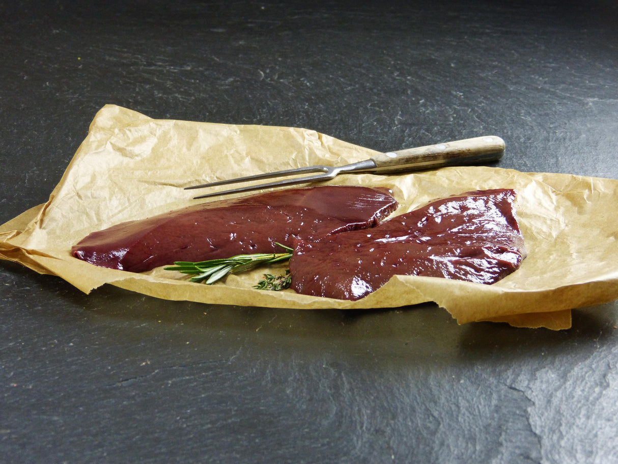 Schweine Leber auf Backpapier mit Thymianzweig und Fleischgabel auf Schieferhintergrund