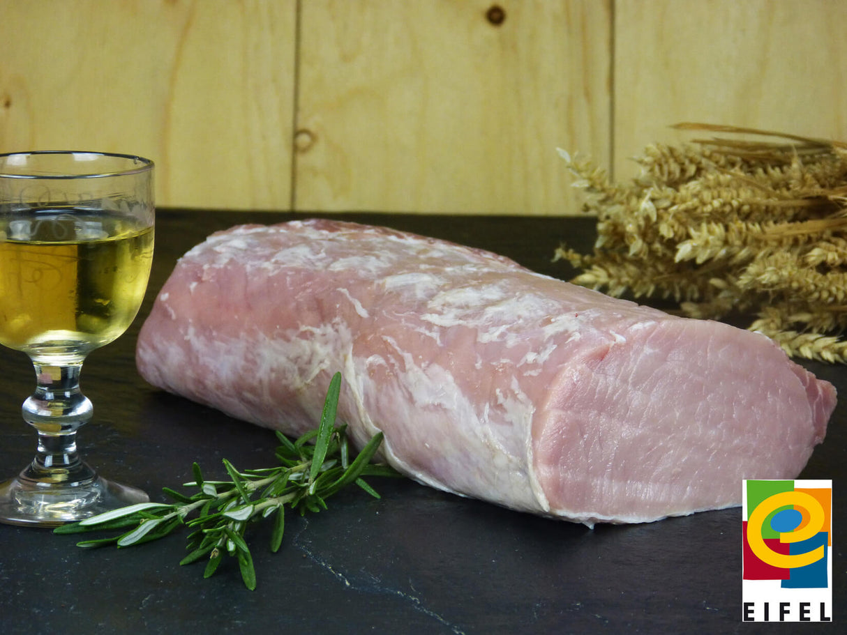 Schweinelachs vom EIFEL Schwein angerichtet mit Thymian Weizen und einem Weinglas auf einem Schieferholzhintergrund Im Vordergrund rechts das Regionalmarke EIFEL Logo