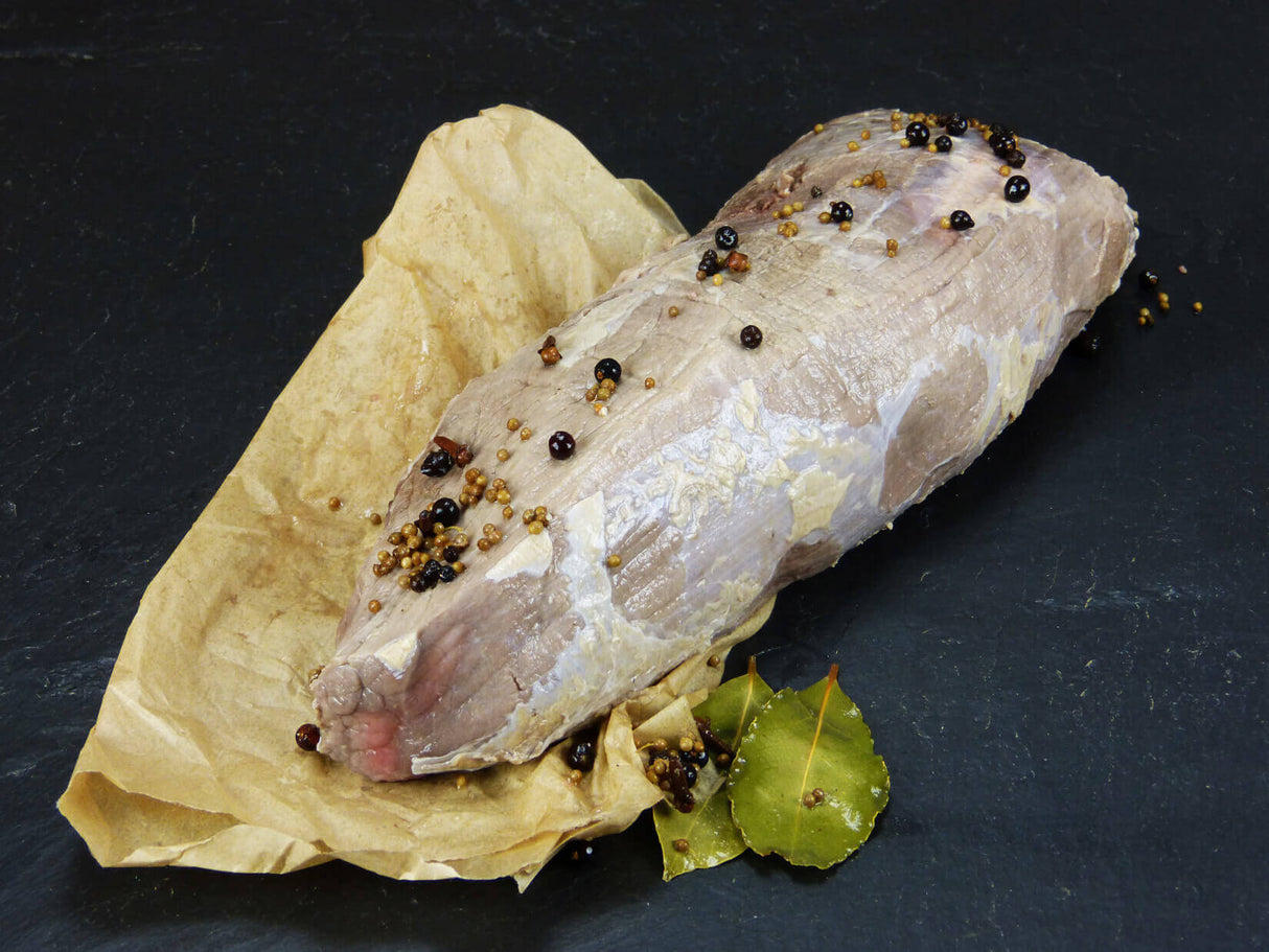 Rinder Sauerbraten aus der Semerrolle angerichtet mit Lorrbeerblättern Wacholderbeeren und Senfkörnern auf einem Stück Backpapier mit Schieferhintergrund