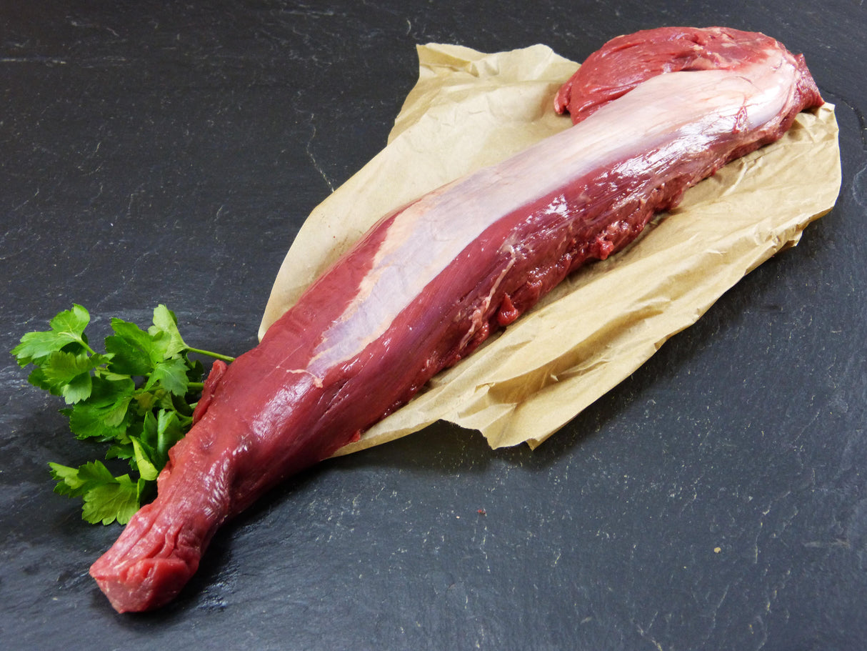 Argentinisches Rinderfilet auf Backpapier mit glatter Petersilie auf Schieferhintergrund