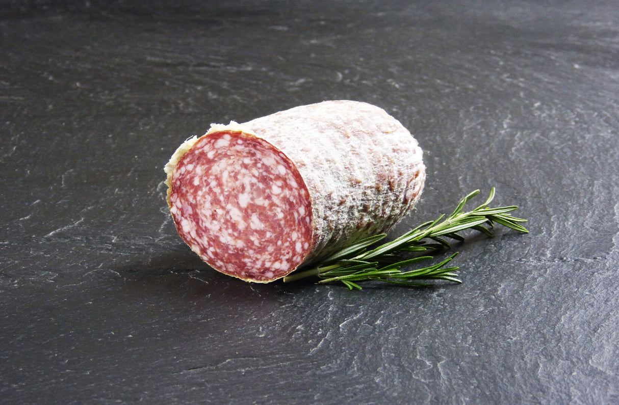 Mailänder Salami am Stück mit Thymian auf Schieferhintergrund