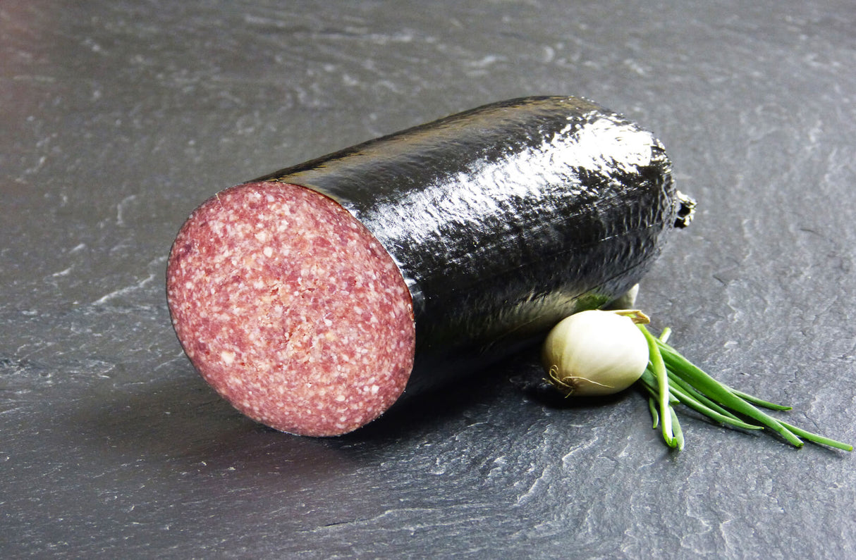 Rindersalami mit Schnittlauch und Knoblauch auf Schieferhintergrund