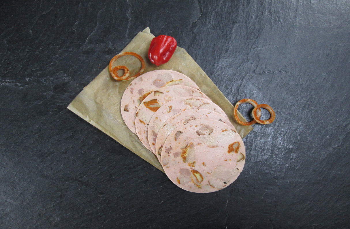 Fünf Scheiben Spießbratenwurst vom EIFEL Schwein angerichtet mit einer kleinen Paprika und paar Zwiebelringen mit Paprika gewürz drauf auf Backpapier mit Schieferhintergrund