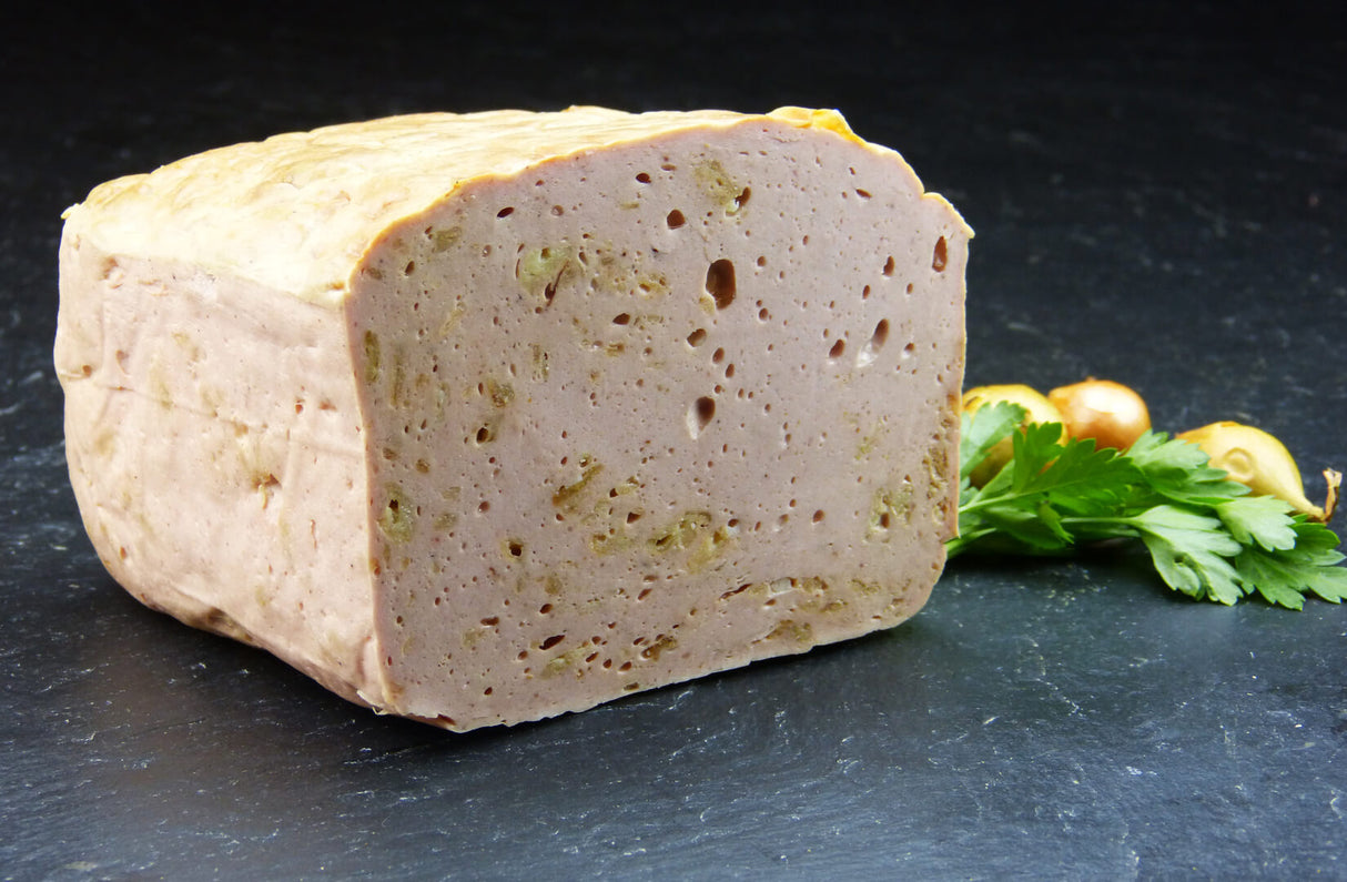 Ein halber Zwiebelfleischkäse gebacken vom EIFEL Schwein angerichtet mit Petersilie und drei Zwiebeln auf Schieferhintergrund