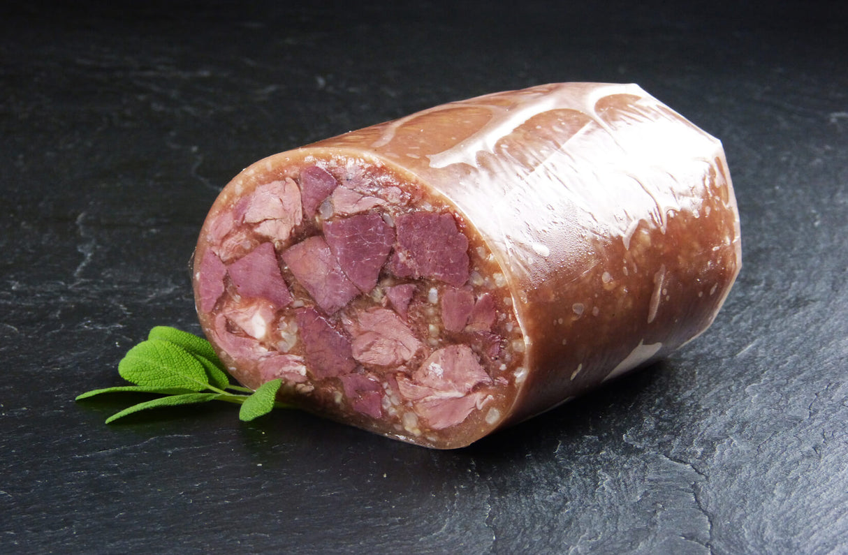 hälfte vom Schwartenmagen mit Rindfleisch angerichtet mit Minze auf Schieferhintergrund