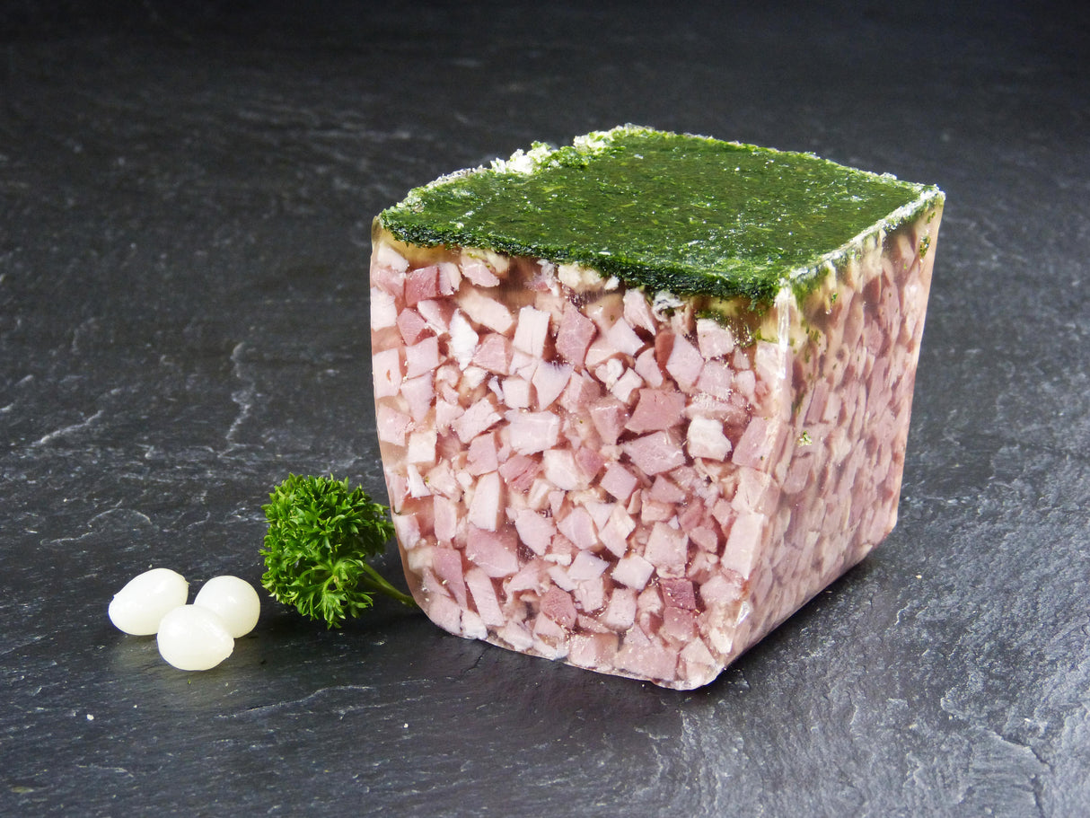 Ein halbe Winzersülze angerichtet mit Silberzwiebeln und Petersilie auf Schieferhintergrund