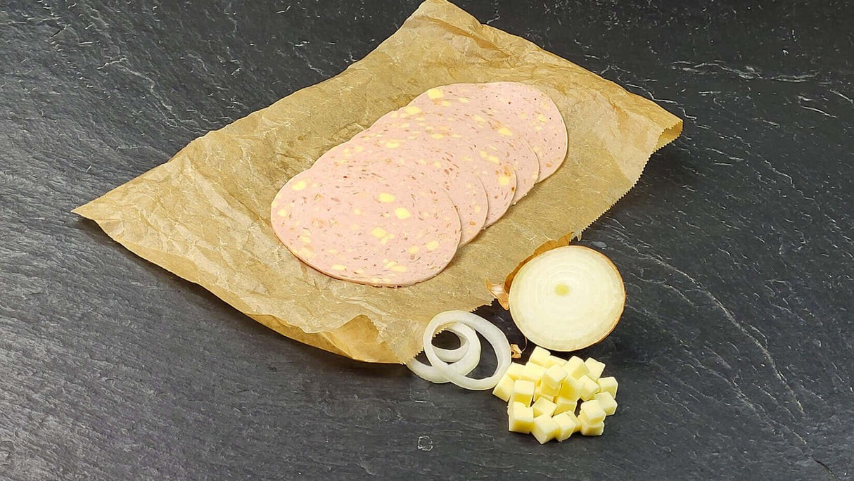 Fünf scheiben Lyoner Cheese und Onions vom EIFEL Schwein angerichtet mit einer halben Zwiebel Käsewürfeln und Zwiebelringen auf Backpapier mit Schieferhintergrund