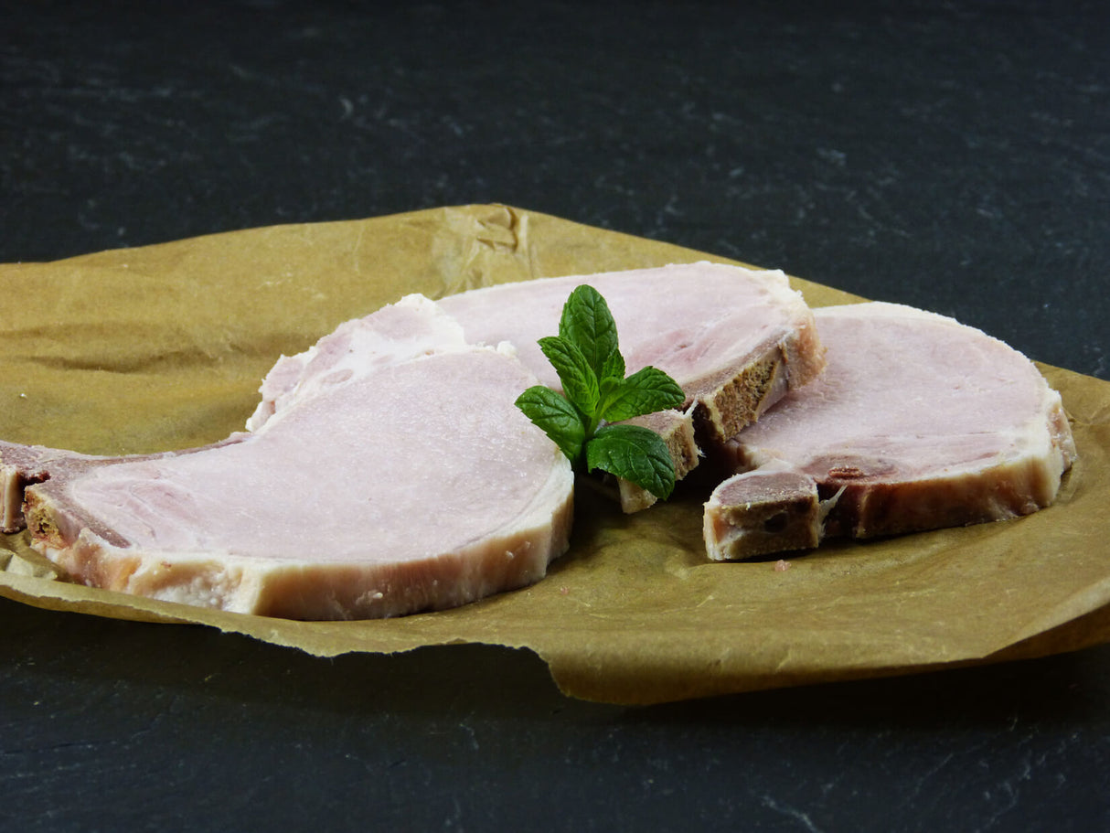Drei Kochrippchen angerichtet mit Minze auf Backpapier mit Schieferhintergrund