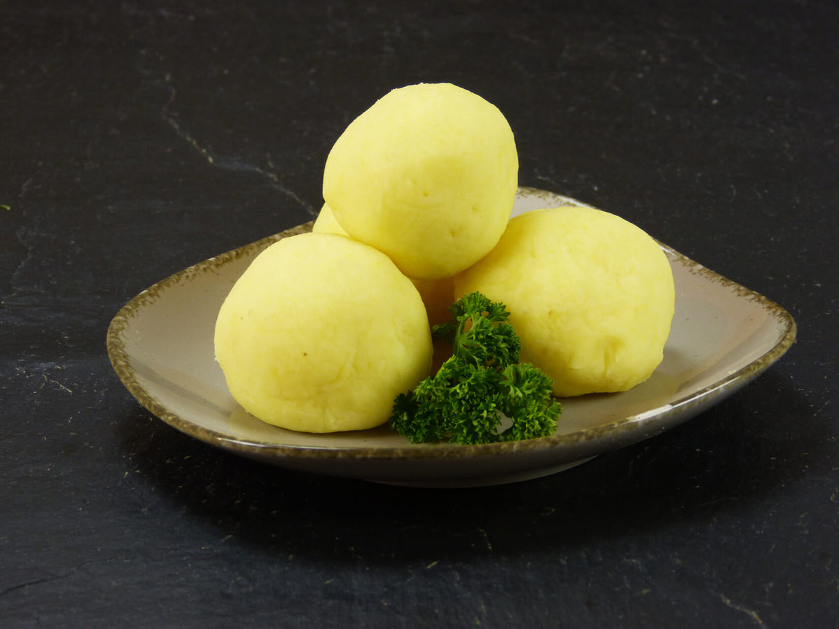 Kloßteig frisch zu drei Kartoffelklößen geformt auf Teller auf Schieferhintergrund