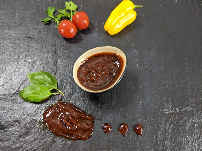 Barbecue Marinade angerichtet mit Petersilie Tomaten Basilikum und einer gelben Paprika