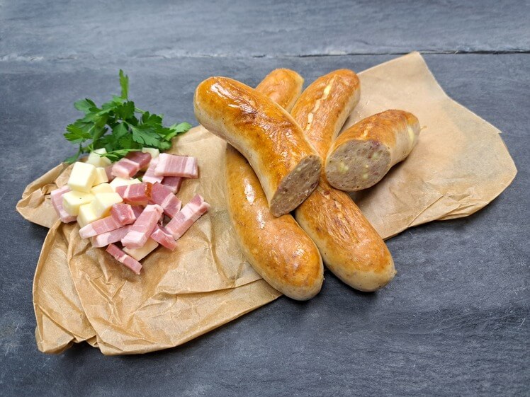 Bratwurst Bacon Cheese gebraten mit Käsewürfeln und Baconwürfeln aus Schieferhintergund