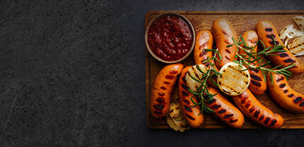 Gebratene Würstchen mit einer gebratenen Zwiebel und Rosmarien Zweigen und einer Schale Dip