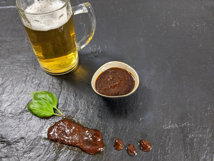 Braumeister Marinade mit einem Bier und zwei blättern basilikum auf Schieferhintergrund angerichtet