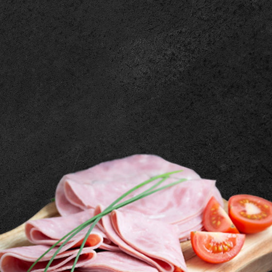 Aufschnitt angerichtet auf Holzbrett, dekoriert mit Tomaten und Schnittlauch mit schwarzem Hintergrund