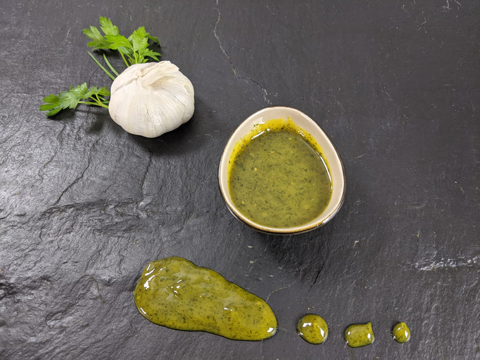 Kräuter Knoblauch Marinade angerichtet mit  Petersilie und Knoblauch auf Schiefer Hintergrund