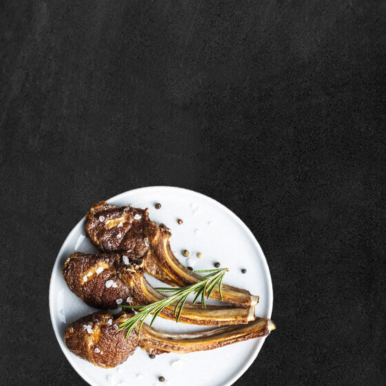 Weißer Teller mit Lammfleisch auf Schieferhintergrund