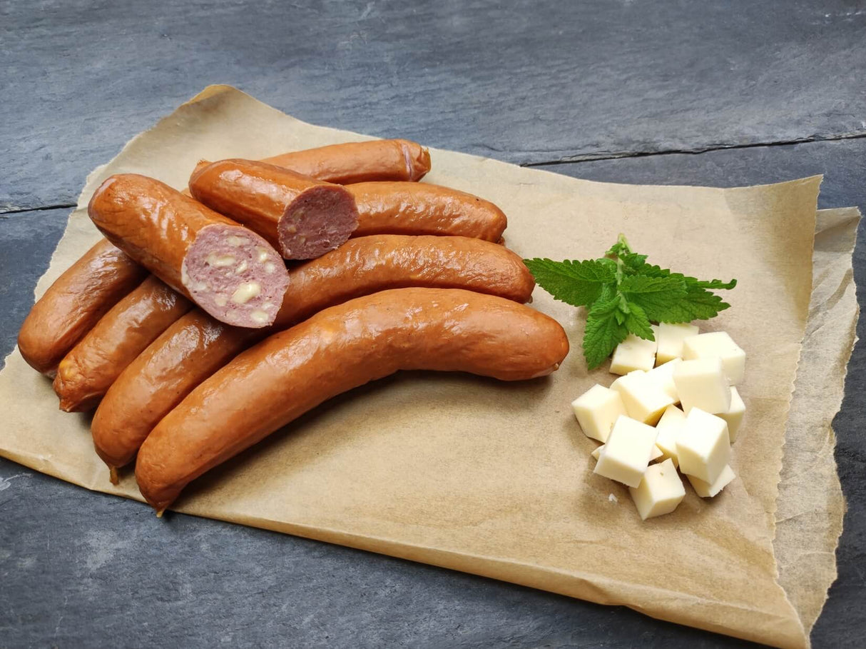 Rindswurst mit Käse vom EIFEL Rind roh mit Käsewürfeln und Minze auf Backpapier und Schieferhintergrund