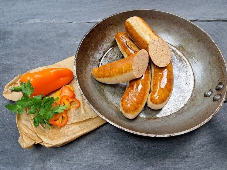 Rostbratwurst Tex Mex gebraten in der Pfanne mit Parika auf Schieferhintergund