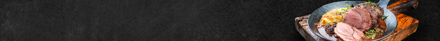 Schweinebraten in Gußpfanne mit Kartoffelbeilage Nahaufnahmen