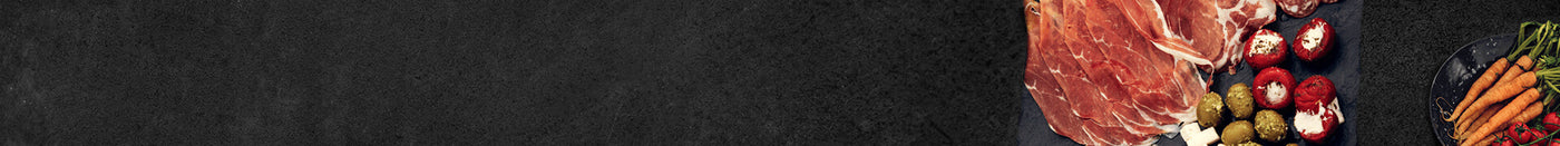 Seranoschinken mit verschiedener Antipasti und Möhren auf Schieferhintergrund