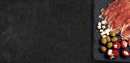 Seranoschinken mit verschiedener Antipasti auf Schieferhintergrund