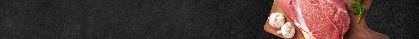 Rohes Fleischstück vom Eifelrind auf Holzbrett dekoriert mit Knoblauch und Petersilie auf schwarzem Hintergrund