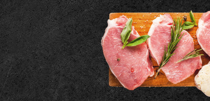 Rohe Steaks vom schwein angerichtet auf Holzbrett und dekoriert mit Kräutern