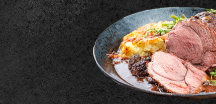 Braten mit Sauce und Kartoffelgratin angerichtet im Teller auf schwarzem Hintergrund