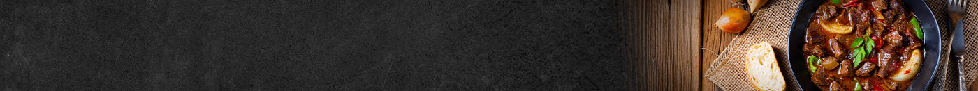 Fertiges Gulasch im Topf dekoriert mit einer Scheibe Baguette und gelben Zwiebeln schwarzer Hintergrund