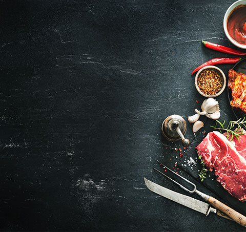 Banner Schieferhintergrund mit Auszug von Fleischstück Kräutern Gewürzen und Besteck