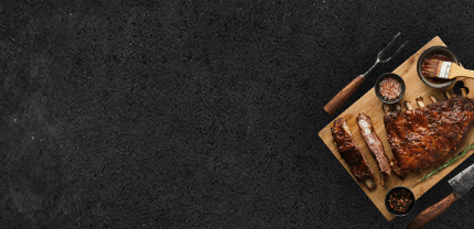 Spare Ribs gegrillt zum Teil aufgeschnitten auf Schieferhintergrund