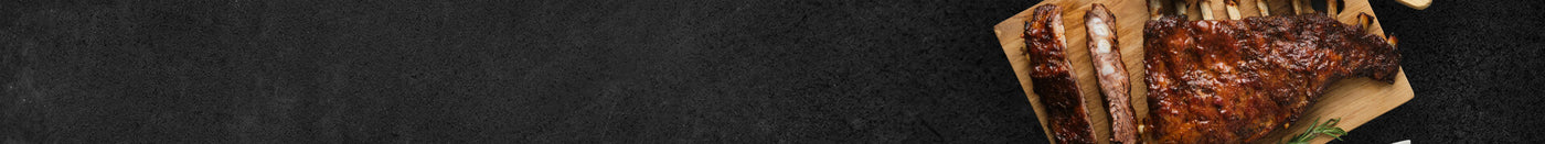 Spare Ribs gegrillt zum Teil aufgeschnitten auf Schieferhintergrund Nahaufnahme