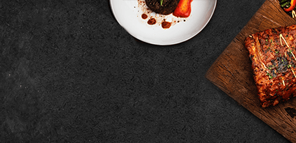 Steak auf Holzbrett mit einem weißen Teller mit Paprika auf Schieferhintergrund