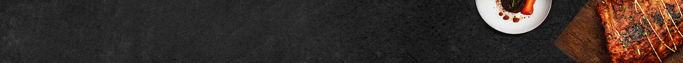 Steak auf Holzbrett mit einem weißen Teller mit Paprika auf Schieferhintergrund