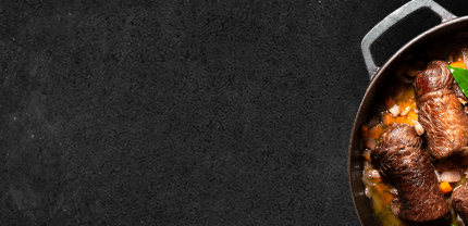 gegarte Rinder Rouladen mit Sauce in Gußpfanne auf Schieferhintergrund