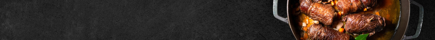 gegarte Rinder Rouladen mit Sauce in Gußpfanne auf Schieferhintergrund