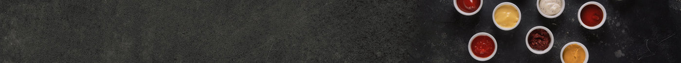 Sieben verschiedene Saucen in Schüsseln angerichtet auf schwarzem Hintergrund