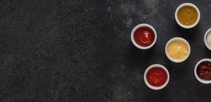 Fünf verschiedene Saucen in Schüsseln angerichtet auf schwarzem Hintergrund