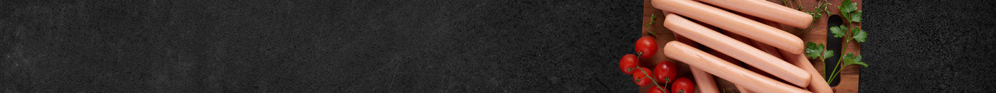 Siedewürstchen auf Holzbrett dekoriert mit Strauchtomaten und Petersilie auf schwarzem Hntergrund