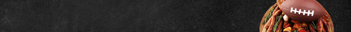 Holzbrett mit einem Football Rosmarien Bratwürstchen Zwiebeln und Paprika auf Schieferhintergrund