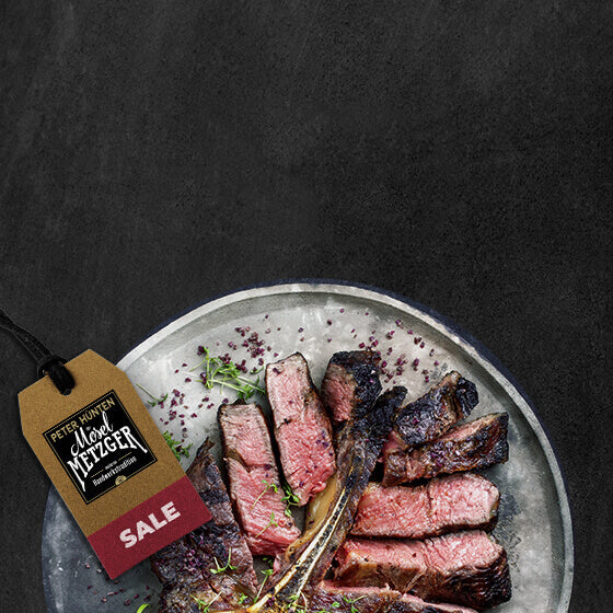 gebratenes angeschnittenes T Bone Steak auf Teller mit dem Hinweisschild Sale auf Schieferhintergrund