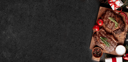 Rindersteaks gebraten mit Tomatendeko auf Holzbrett auf Schieferhintergrund