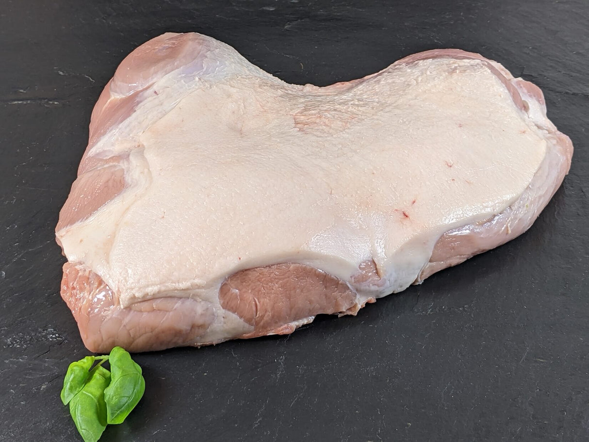 Schinken ohne Knochen mit Schwarte auf Schieferhintergrund