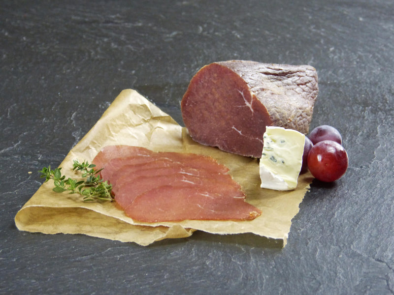Rinder Rauchfleisch etwas in Scheiben aufgeschnitten mit Blauschimmelkäse und Trauben auf Schieferhintergrund