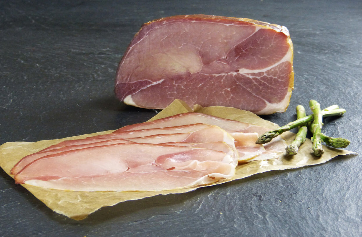 Rohschneider geschnitten mit grünem Spargel auf Schieferhintergrund