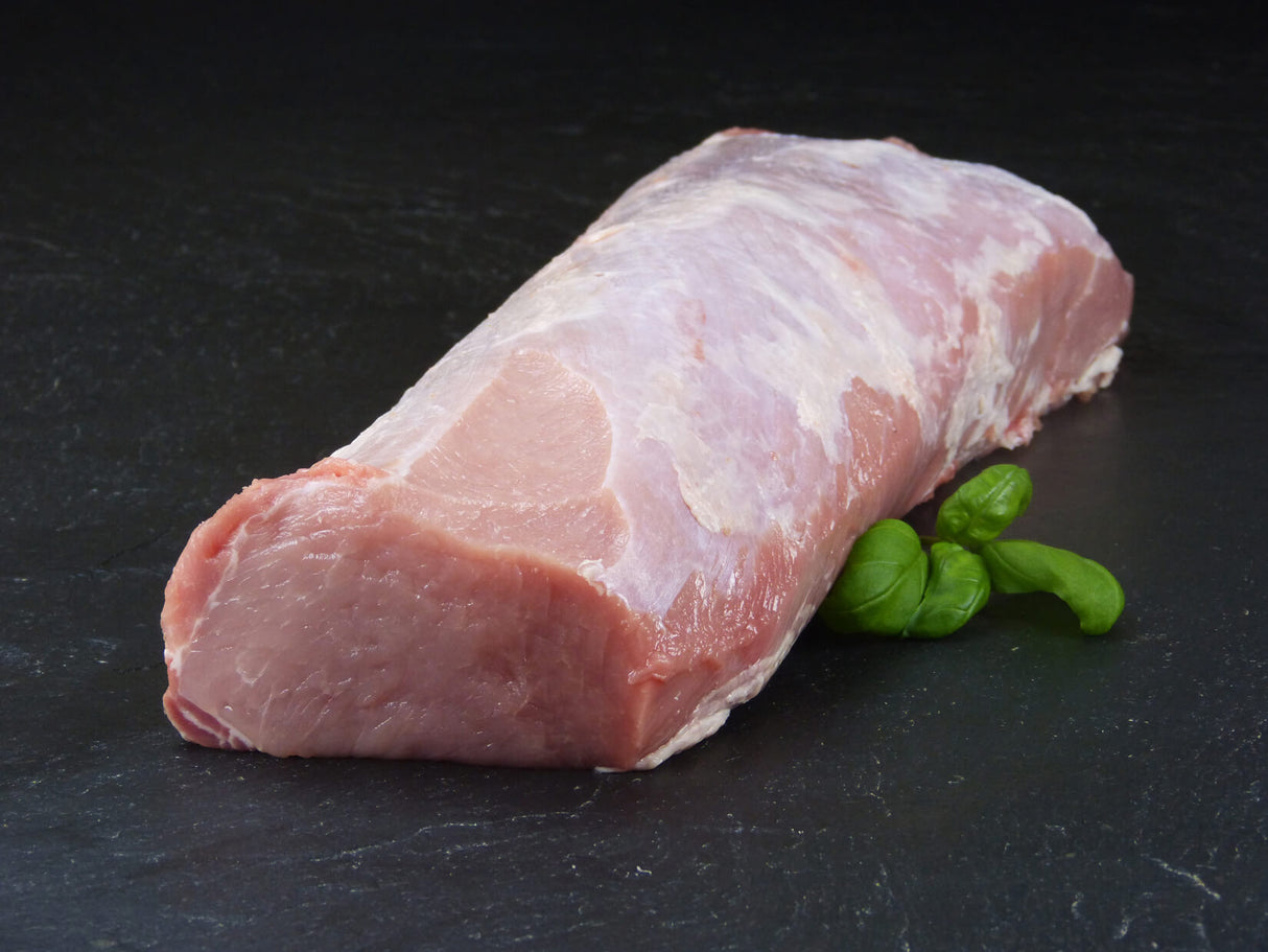 Schweinelachs am Stück mit Basilikum auf Schieferhintergrund