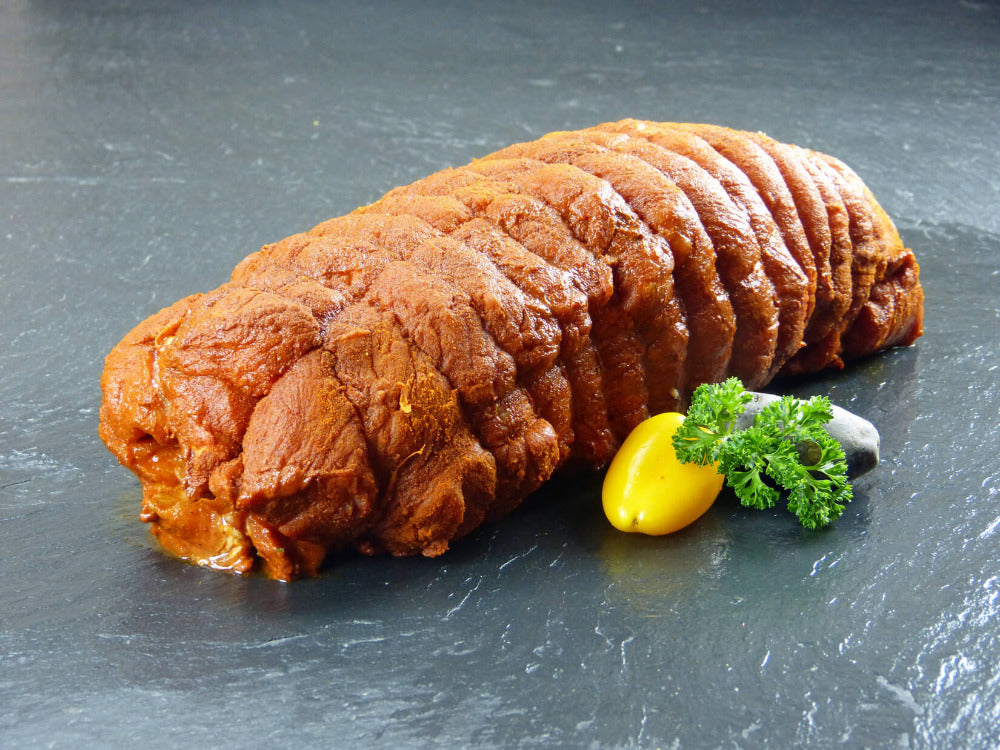 Kammspießbraten handgerollt mit gelber Paprika und roter Katoffel und Petersilie auf Schieferhintergrund